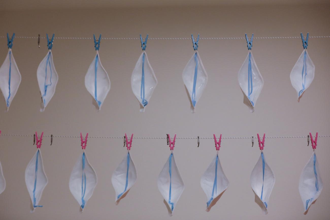Picture shows two rows of protective masks tacked to a wall.